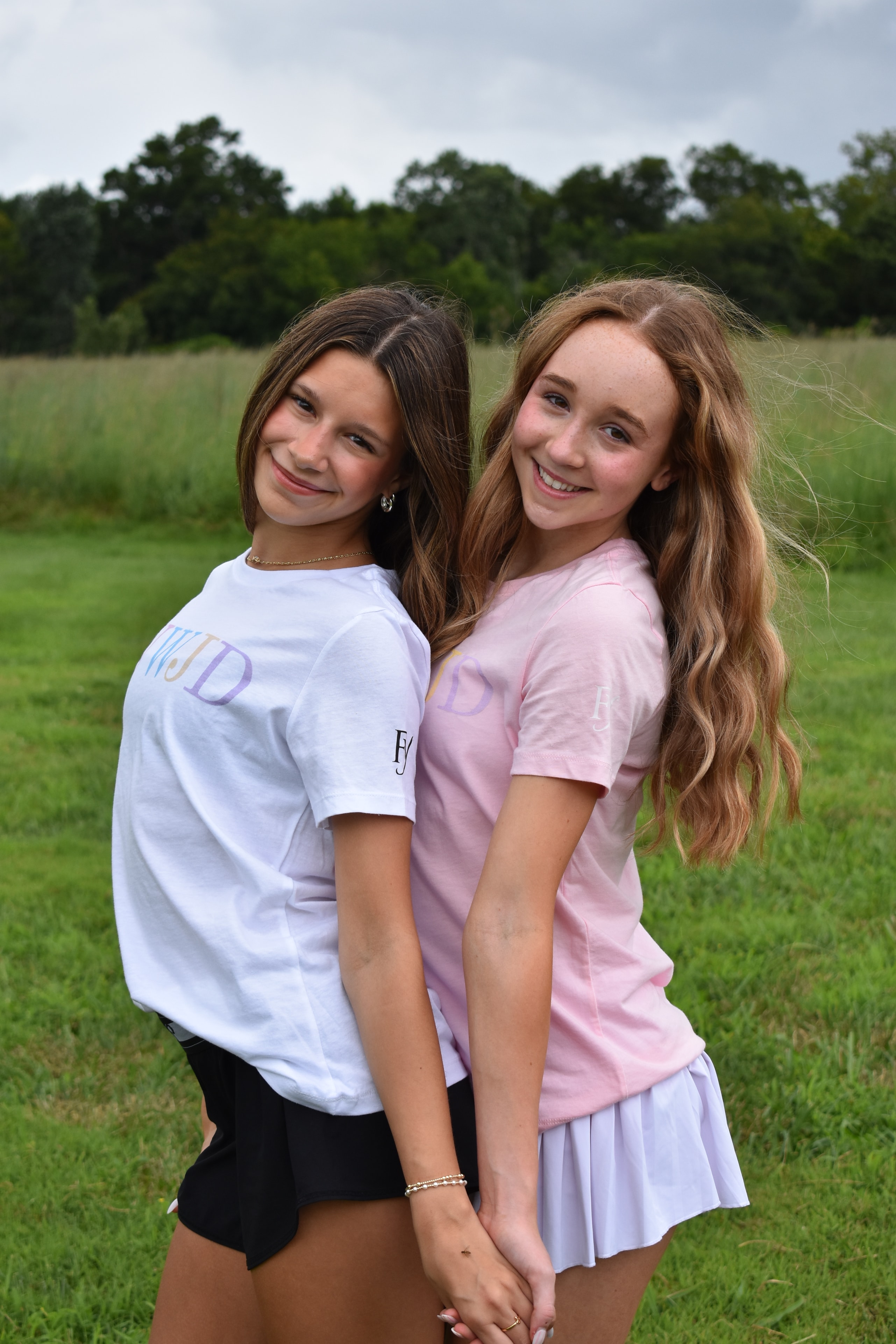 Two teenage girls smiling in a grassy field